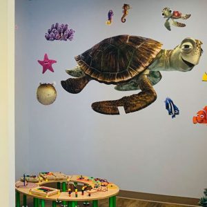 The kids area of the dentist office features a large wall sticker of Crush, the sea turtle from the movie Nemo.