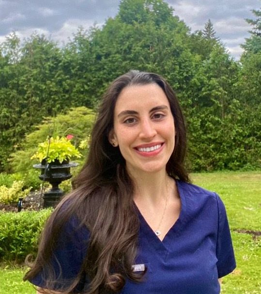 Dr. Christine, pediatric dentist at Just for Kids in Maine, smiles in front of a garden